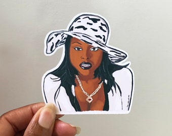 May include: A die-cut sticker featuring an illustration of a person with long dark hair wearing a white and black cow-print wide-brimmed hat, a white collared shirt with black trim, and a silver chain necklace with a central pendant.