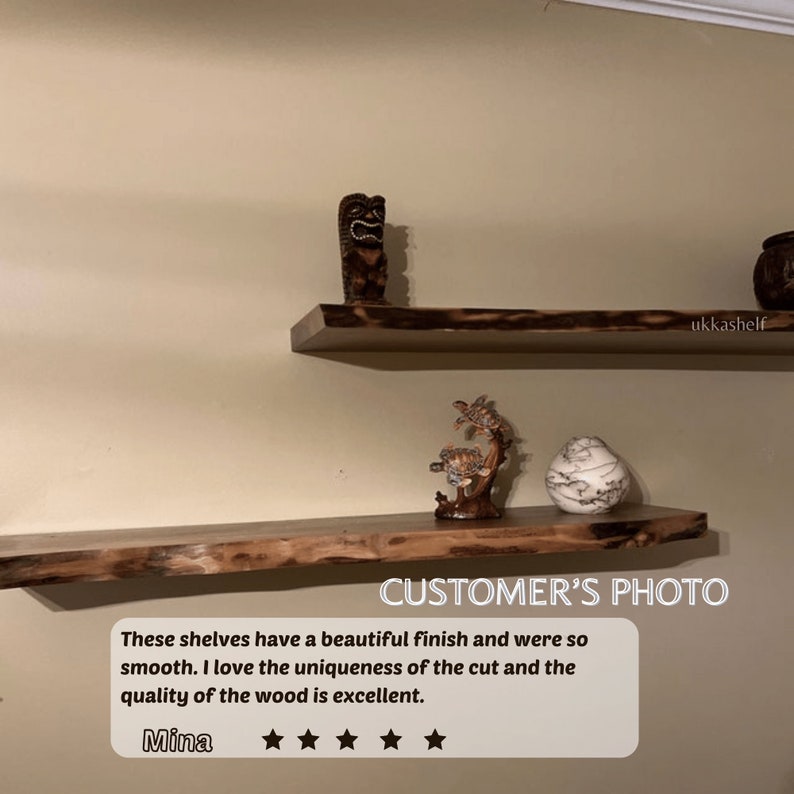 May include: Two wooden shelves with live edge details. The top shelf has a wooden tiki statue and the bottom shelf has a wooden turtle statue and a white ceramic vase. The shelves are mounted on a beige wall. "CUSTOMER'S PHOTO" is written in white text on a black rectangle at the bottom of the image. The text "These shelves have a beautiful finish and were so smooth. I love the uniqueness of the cut and the quality of the wood is excellent. Mina" is written in white text on a black rectangle at the bottom of the image. Five white stars are below the text.