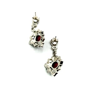 The back view of two silver earrings with red carnelian centers and marcasite accents, showing the posts and clasps on a white background.