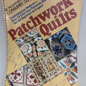 May include: A spiral-bound instructional book titled Patchwork Quilts by the Editors of Consumer Guide. The tan cover features large maroon text and four inset photographs displaying various quilt designs, patterns, and needlework illustrations.