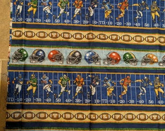May include: A cotton fabric panel featuring a repeating American football theme. The design includes rows of football players in various uniforms on a field with yard lines, rows of footballs spelling FOOTBALL, and rows of colourful helmets.
