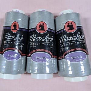 May include: Three spools of silver gray Maxi-Lock serger thread, each with a red sewing machine logo and the text "Maxi-Lock Serger Thread" and "$4.59".