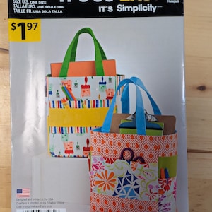 May include: A sewing pattern for two tote bags. The bags are made of fabric with different patterns, including paintbrushes, flowers, and geometric designs. The pattern is called "It's So Easy" and is from Simplicity.