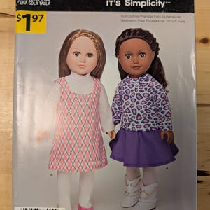 May include: A sewing pattern for doll clothes, featuring two dolls wearing the outfits. The pattern is for 18 inch dolls and is titled "It's So Easy It's Simplicity".