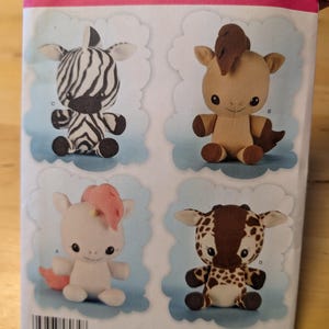May include: A sewing pattern for making four plush toys: a zebra, a horse, a unicorn, and a giraffe. The pattern is from Simplicity and is for one size. The pattern number is 8034.