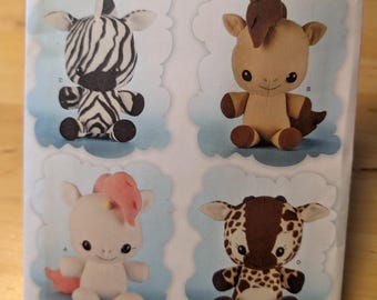 May include: A sewing pattern for making four plush toys: a zebra, a horse, a unicorn, and a giraffe. The pattern is from Simplicity and is for one size. The pattern number is 8034.
