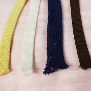 May include: Four different colors of elastic ribbon, yellow, white, navy blue, and brown.