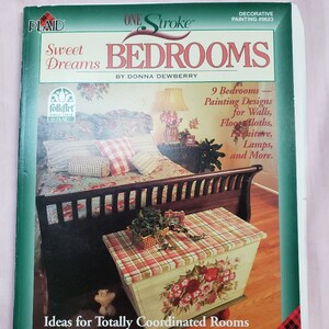 May include: A book cover titled "Sweet Dreams Bedrooms" by Donna Dewberry. The cover features a bedroom scene with a bed, chest, and floral accents. The book is part of the "One Stroke" decorative painting series.