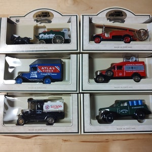 May include: A collection of ten vintage toy trucks in individual boxes. The trucks are all different colors and have various logos and branding, including "Polarine", "Atlas Tires", "Standard Oil", and "Red Crown".