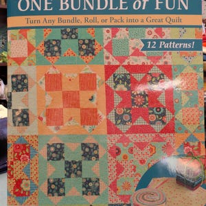 May include: A book titled "ONE BUNDLE of FUN" by Sue Pfau, featuring colorful quilt patterns. The cover displays various quilt block designs in shades of orange, teal, and floral prints. The book promises 12 patterns for creating quilts from bundles, rolls, or packs.