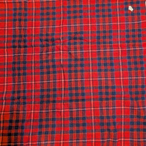 May include: Red and black plaid throw blanket with fringe on the bottom edge.