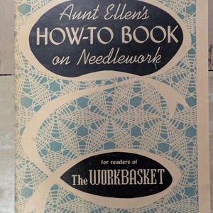 May include: A vintage softcover book titled Aunt Ellen's HOW-TO BOOK on Needlework for readers of The WORKBASKET. The cover features a light blue background with a white lace-like spiderweb pattern and two black oval shapes containing white text.