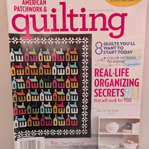 May include: A magazine cover for "American Patchwork & Quilting" featuring a quilt with colorful house designs. The cover includes text about quilting tips, organizing secrets, and new designs. The magazine is dated February 2017.