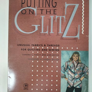 May include: A book cover with the title "PUTTING ON THE GLITZ" in large, stylized letters. The cover is a reddish-brown color with the text "UNUSUAL FABRICS & THREADS FOR QUILTING AND SEWING". A woman in a colorful jacket is pictured on the right.