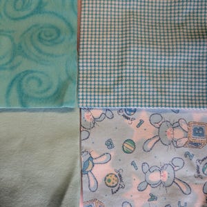 May include: A baby quilt with a blue and white checkered pattern, a light blue swirl pattern, and a light blue background with a white bunny pattern and the words "Sweet Dreams".