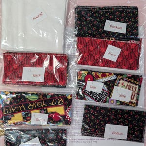 May include: A set of fabric squares for a sewing project. The squares are labeled with numbers and names, such as "Flannel", "Back", "Front", "Pockets", "Sides", "Bottom", and "Put Your Heart".