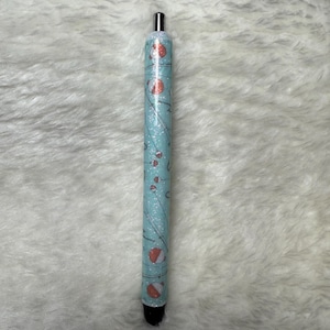 May include: A blue and white pen with a glitter finish and a design of fishing lures and bobbers.