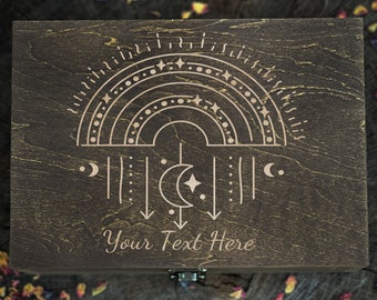 May include: A wooden box with a dark brown stain and a light brown design of a crescent moon, stars, and a rainbow. The text "Your Text Here" is engraved on the box.