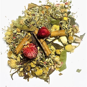 May include: A close-up shot of a pile of loose-leaf herbal tea. The tea blend includes dried chamomile flowers, lavender, cinnamon sticks, and red globe amaranth flowers. The tea leaves are a mix of green and brown, with a white background.