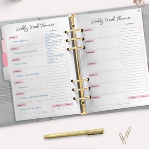 May include: A weekly meal planner with a grocery list and space to write in meals for each day of the week. The planner is open to a page with a list of groceries, including pizza base, mozzarella cheese, salami, chicken thigh, arborio rice, steak, lettuce, tomato, butternut pumpkin, potato, and salmon.