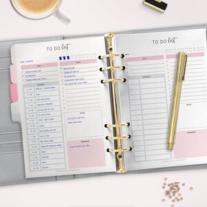 May include: A gray and pink daily planner with a gold binder and a gold pen. The planner has a to-do list, schedule, and notes sections. The planner is open to a page with the date 01/08/2023.