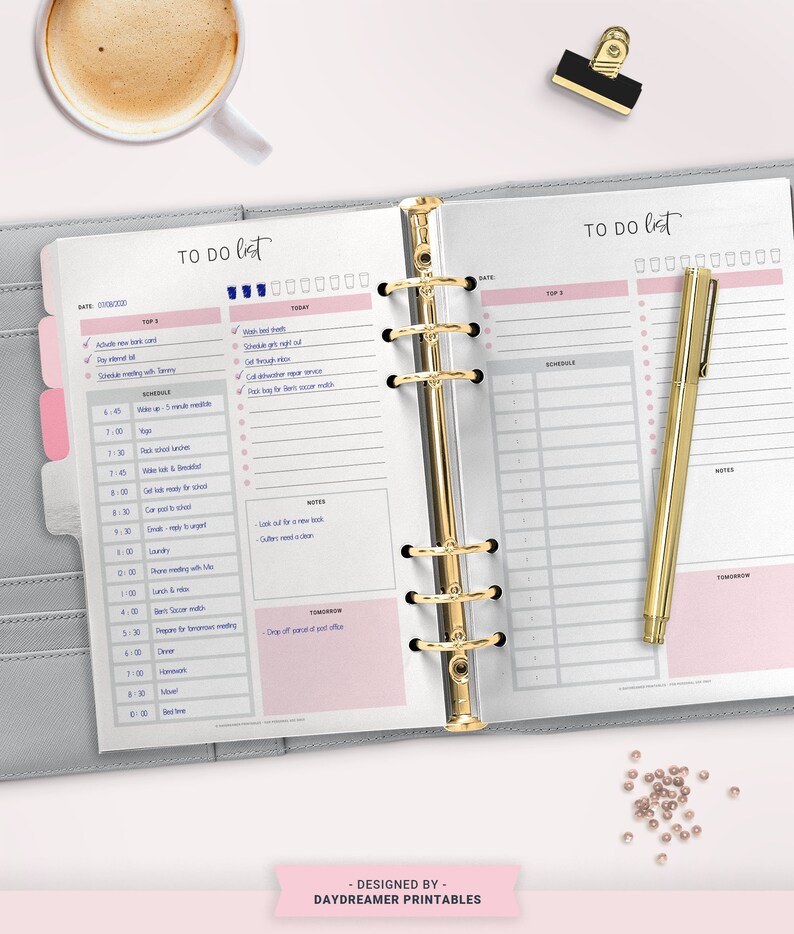 May include: A gray and pink daily planner with a gold binder and a gold pen. The planner has a to-do list, schedule, and notes sections. The planner is open to a page with the date 01/08/2023.