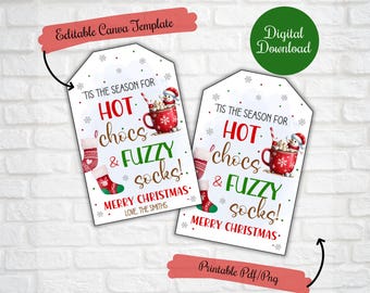 Pode incluir: Duas etiquetas de presente brancas com ilustrações vermelhas e verdes de chocolate quente, meias felpudas e um boneco de neve. O texto nas etiquetas diz "Tis the season for hot chocs & fuzzy socks! Merry Christmas."