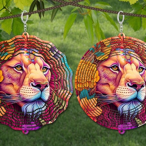 May include: Two colorful metal wind spinners with a lion's face design. The spinners are circular and have a layered design with intricate details. The lion's face is depicted in a vibrant pink, orange, and blue color scheme.