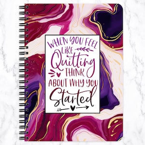 May include: Spiral-bound notebook with a cover featuring a swirling design in shades of purple, magenta, and gold. The notebook has the text "When you feel like quitting, think about why you started" in a white box.