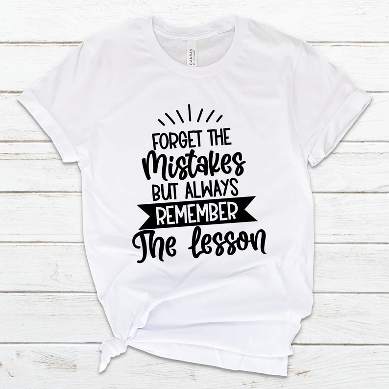 May include: White t-shirt with black text that reads "Forget the mistakes but always remember the lesson".