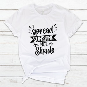 May include: White t-shirt with black text that reads "spread sunshine not shade".