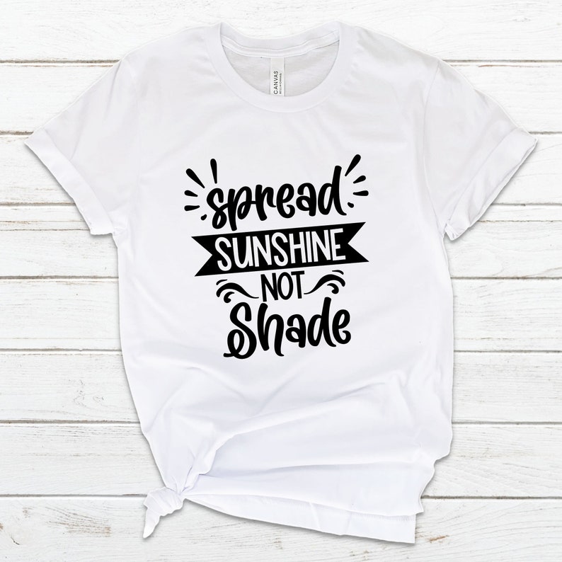 May include: White t-shirt with black text that reads "spread sunshine not shade".