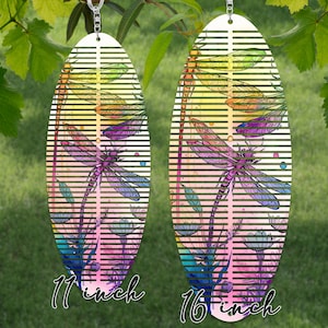 Puede incluir: Dos carillones de viento de metal con forma de libélula, uno de 28 cm y otro de 41 cm, con un diseño a rayas de colores y una silueta de libélula.