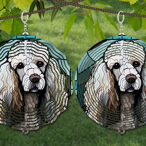 May include: A pair of white poodle dog earrings with a stained glass design. The earrings are round and have a blue and green background.