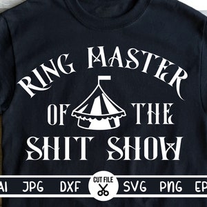 May include: A black t-shirt with white text that reads "Ring Master of the Shit Show". A white circus tent graphic is between the words "of" and "the".