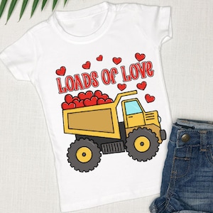 May include: White t-shirt with a yellow dump truck filled with red hearts. The text "Loads of Love" is above the truck.