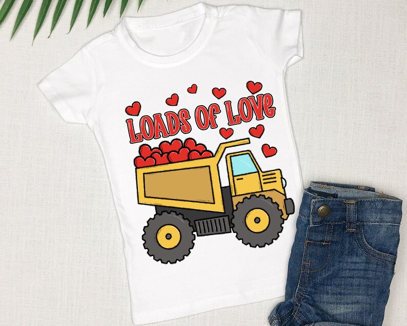 May include: White t-shirt with a yellow dump truck filled with red hearts. The text "Loads of Love" is above the truck.