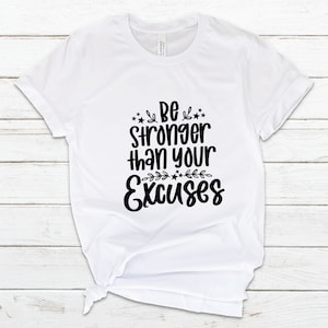 May include: White t-shirt with black text that reads "Be stronger than your excuses" with stars and floral accents.