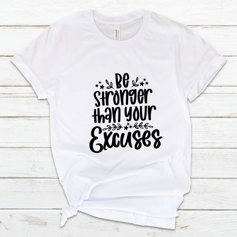 May include: White t-shirt with black text that reads "Be stronger than your excuses" with stars and floral accents.