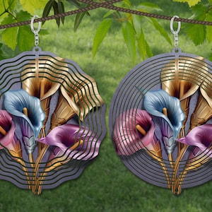 May include: Two metal wind spinners with a design of purple, blue, and gold calla lilies. The spinners are hanging from a rope and are in front of a green grassy background.