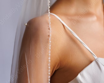 May include: A white bridal veil with a beaded trim. The veil is sheer and delicate, and the beads are small and evenly spaced.