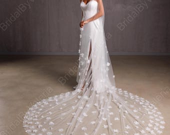 May include: A white bridal veil with a long train and delicate floral appliques. The veil is made of soft tulle and features a delicate floral pattern throughout.