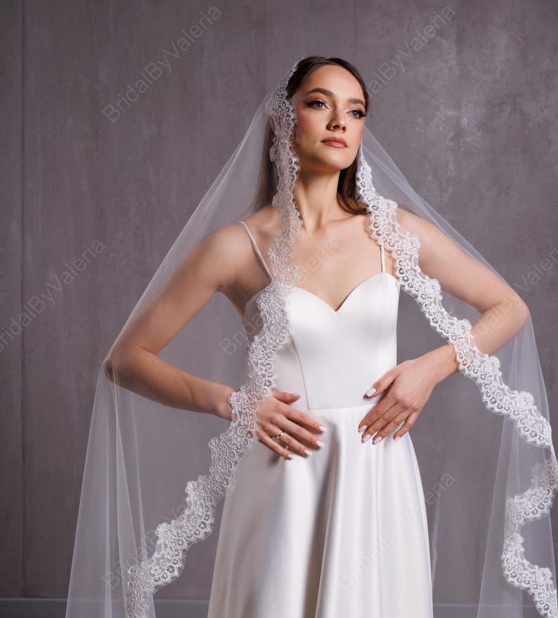 May include: A white bridal veil with a delicate lace trim. The veil is made of soft tulle and is perfect for a wedding ceremony.
