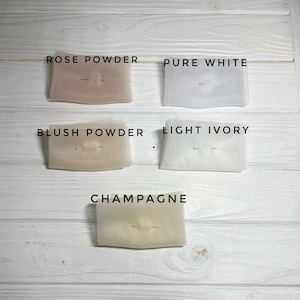 May include: Five fabric swatches in different shades of white and ivory. The swatches are labeled "Rose Powder", "Pure White", "Blush Powder", "Light Ivory", and "Champagne".