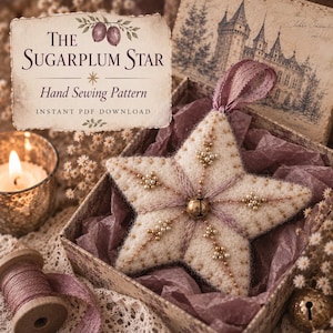 May include: A cream-coloured felt star ornament featuring intricate beadwork, metallic thread embroidery, and a central gold bell. The star includes a mauve ribbon loop for hanging and is presented in a decorative box with text reading The Sugarplum Star Hand Sewing Pattern.