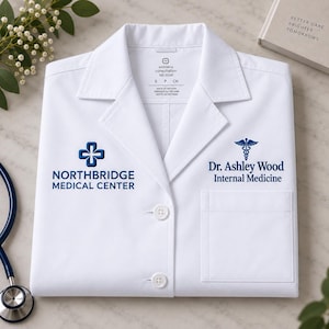 May include: A white lab coat featuring a notched collar, two front buttons, and a chest pocket. The right side displays a blue cross logo and the text NORTHBRIDGE MEDICAL CENTER. The left side features a caduceus symbol and Dr. Ashley Wood Internal Medicine.
