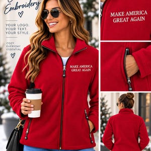 May include: A bright red fleece jacket featuring a full-length black zipper and two side pockets with black zippers. The text "MAKE AMERICA GREAT AGAIN" is embroidered in white on the upper left chest. The jacket has a high collar and long sleeves.
