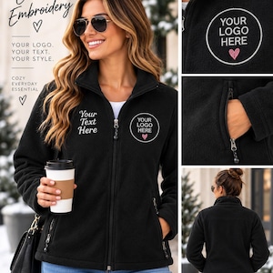May include: A black fleece zip-up jacket featuring custom embroidery options. The front displays text reading Your Text Here and a circular logo with the text Your Logo Here and a small heart icon. It includes zippered side pockets and a high collar.