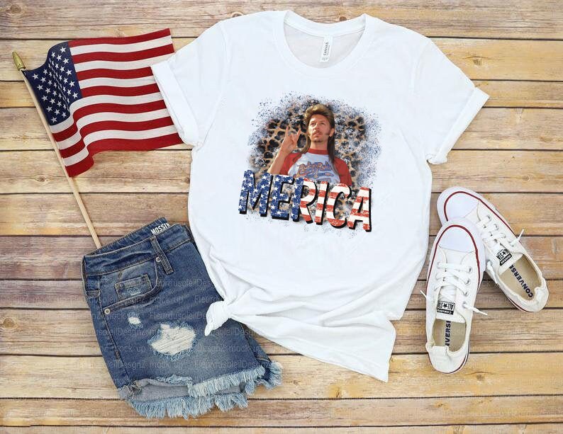 May include: White t-shirt with a red, white, and blue graphic of a man with a beard and the word "Merica" printed on it. The shirt is paired with denim shorts and a pair of white sneakers.