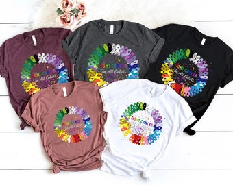 May include: Five t-shirts in different colors with a circle of colorful ribbons and the text "Fight Cancer In All Colors".